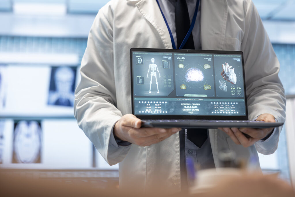 "AI in healthcare: A doctor holds a laptop displaying detailed medical data, including a brain scan, a heart scan, and skeletal information.