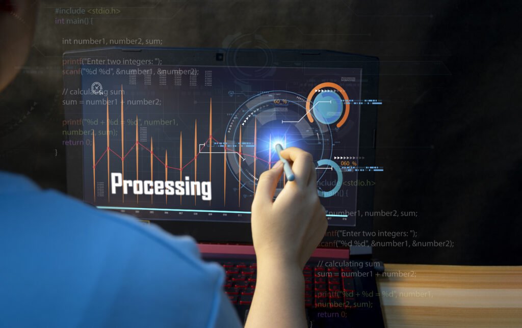 A person is sitting at a desk, looking at a laptop screen. The screen shows a code snippet written in C programming language and a holographic display with a graph and the word "Processing."