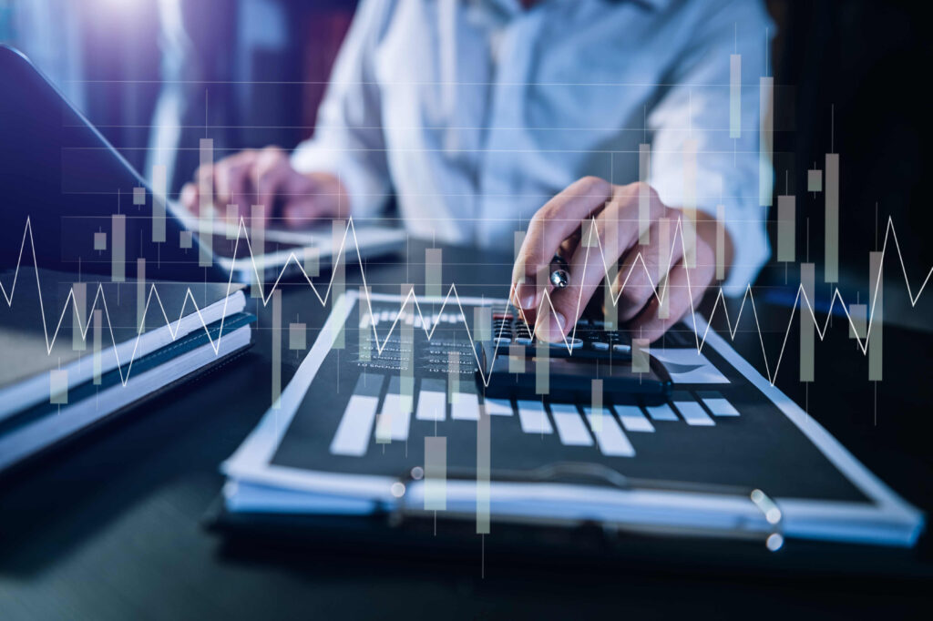 A person using a calculator and laptop while analyzing financial data, illustrating the potential benefits of nearshore software development in streamlining business processes.