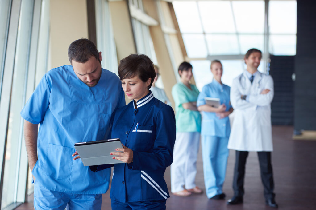 A team of healthcare professionals actively collaborating while using a tablet, emphasizing the role of custom software development in streamlining medical operations. The use of digital tools highlights how adaptive software solutions empower healthcare teams to access, share, and manage critical data, ultimately enhancing patient care and operational efficiency.