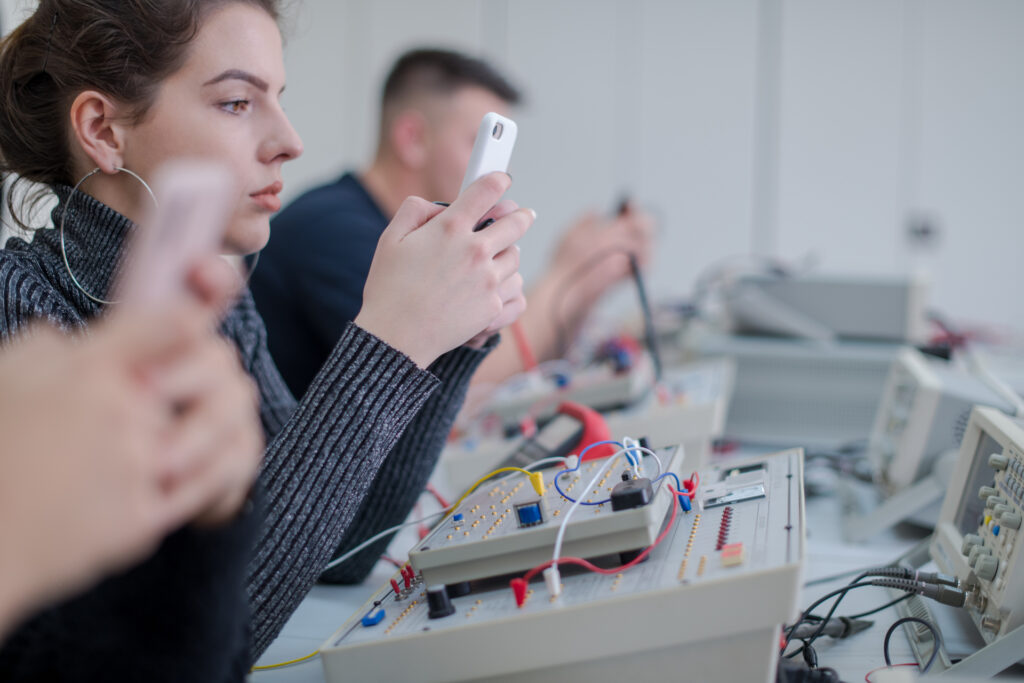 Focused professional using mobile devices and testing equipment in a technical environment, representing the process of A/B testing for optimization.