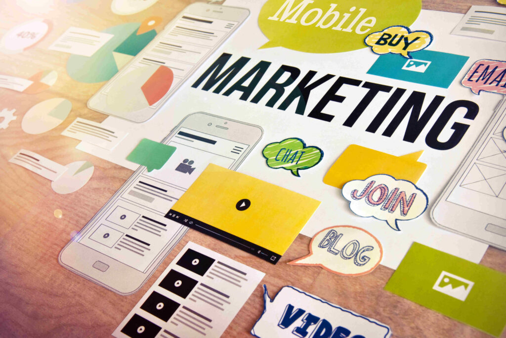 A collage of various marketing elements, including a smartphone, a tablet, speech bubbles with words like "MOBILE," "BUY," "EMAIL," "CHAT," "JOIN," "BLOG," and "VIDEO," and icons representing different marketing strategies