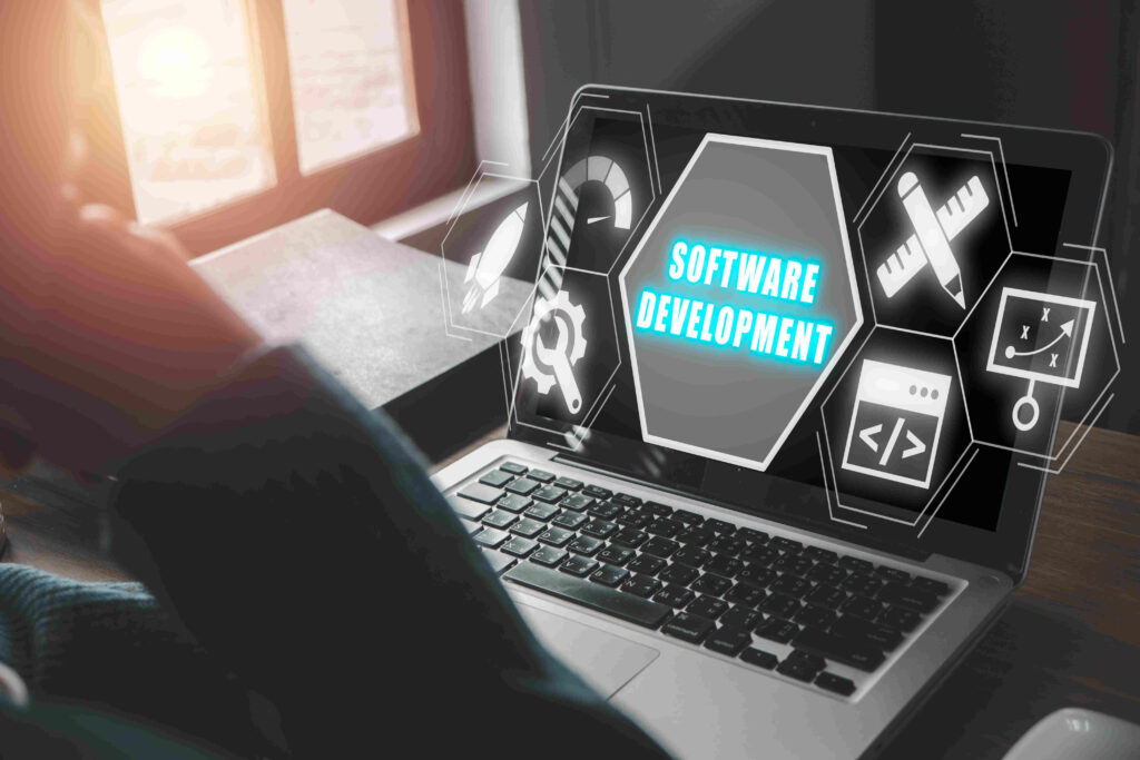 A nearshore software development workspace featuring a laptop with the words "SOFTWARE DEVELOPMENT" and coding icons, along with a person's legs in the foreground.