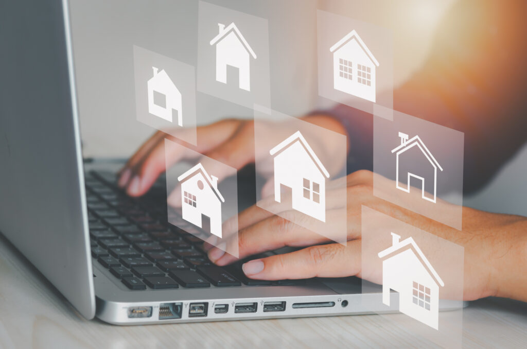 A person using a laptop to manage multiple rental properties, represented by house icons