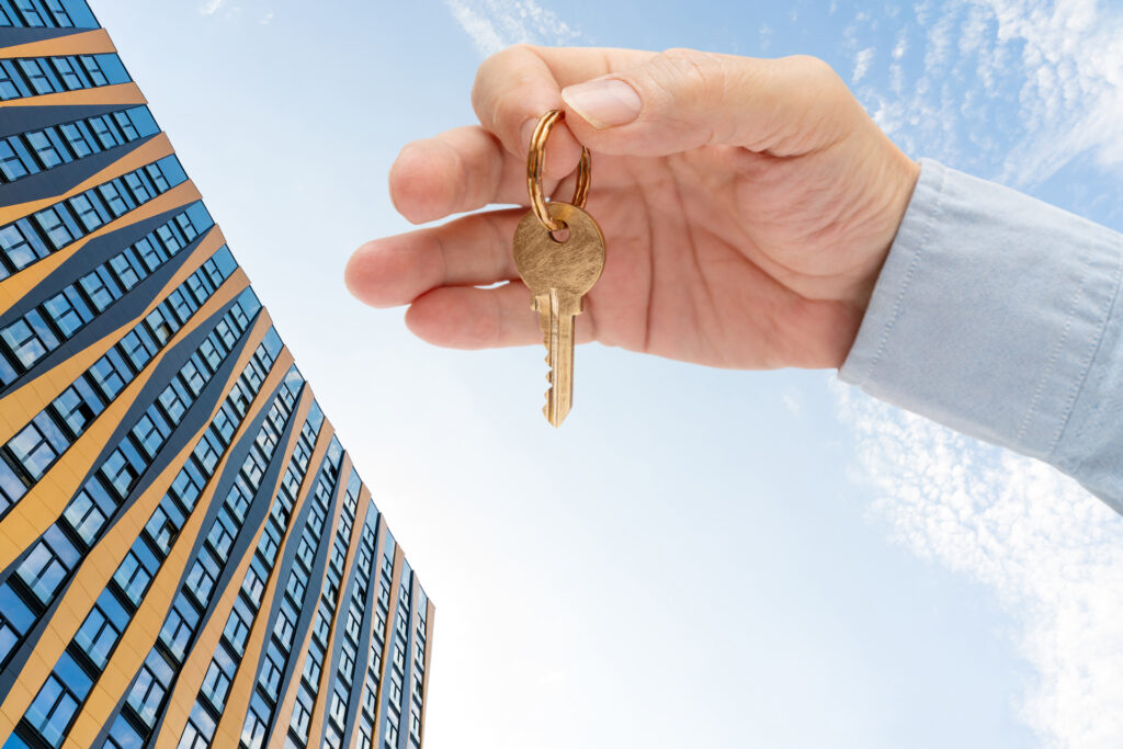 A golden key held up against a backdrop of a modern apartment complex, representing multifamily property management