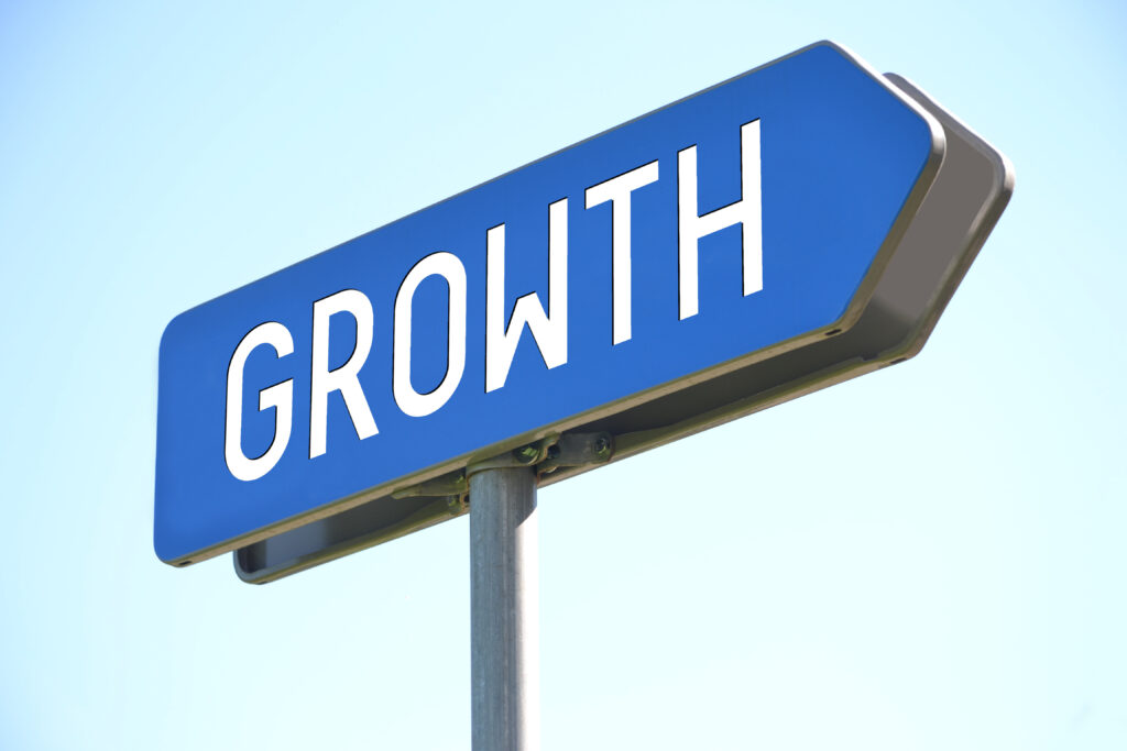 A blue sign with the word "GROWTH" in white, pointing to the right. The sign is against a clear blue sky, symbolizing a clear path to growth.