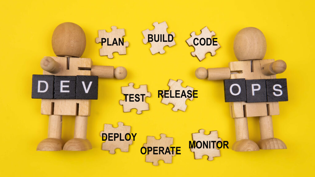 Two wooden figures standing on a yellow background, representing the roles of Development (DEV) and Operations (OPS) in mobile app development