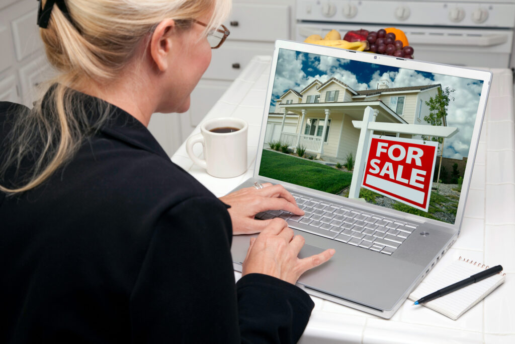 A real estate professional using CRM software on a laptop to manage property listings and sales.