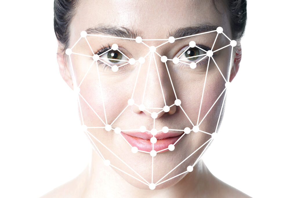 Close-up of a woman's face overlaid with a white geometric grid, representing facial recognition software. The grid consists of interconnected points and lines mapping key facial features, illustrating cutting-edge trends in biometric technology, computer vision, and AI-driven identity verification systems. 