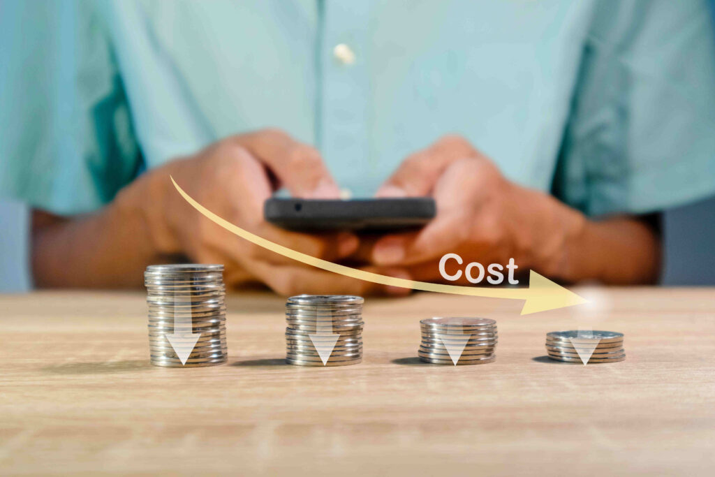 A visual representation of the cost-effective nature of nearshore software development: a person holding a smartphone with a downward-pointing arrow above stacks of coins.