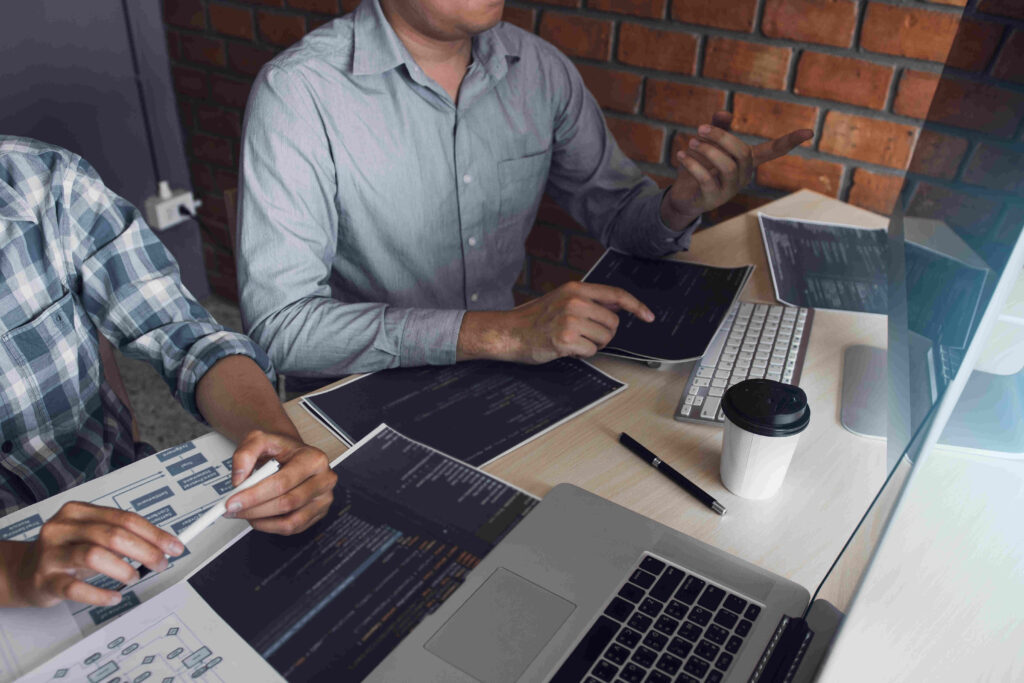 Two developers working collaboratively, analyzing code and diagrams at a desk, representing the strategic planning and teamwork involved in nearshore software development.