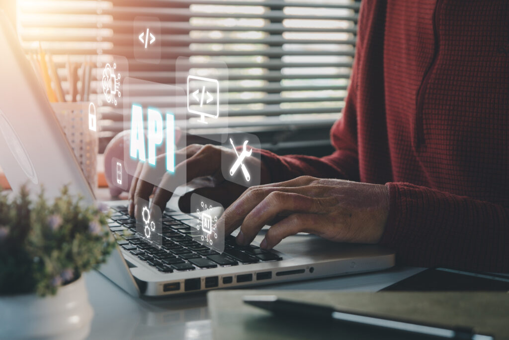 The image shows a person typing on a laptop with various icons representing API frameworks floating above the keyboard. This visual highlights the integration and importance of API frameworks in modern software development.