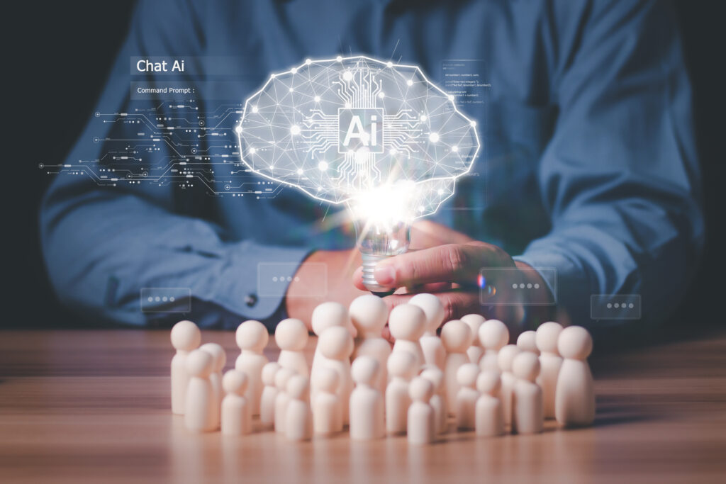 The image shows a business professional interacting with a digital tablet projecting a holographic AI brain, surrounded by small wooden figures. This symbolizes the development of AI sales talent, highlighting innovative training methods and the future of sales strategies.