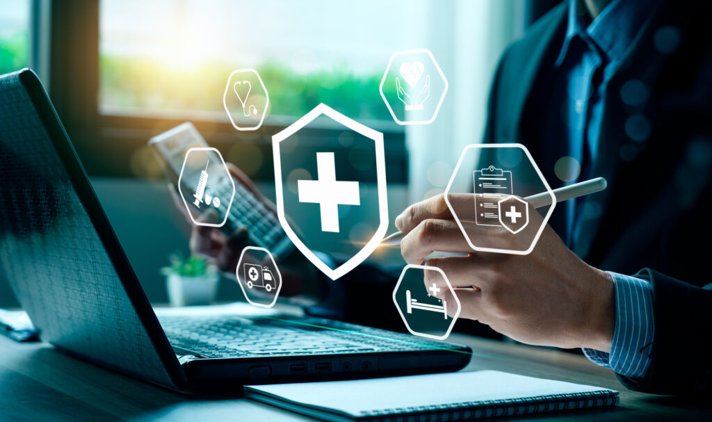 A healthcare professional uses a laptop with healthcare software, emphasizing regulatory compliance. The image highlights the integration of technology to ensure adherence to healthcare standards. 