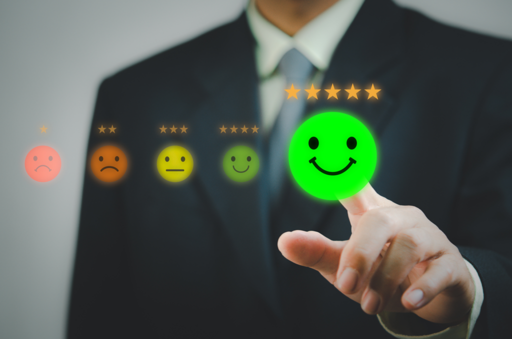 A person in a suit is selecting a green smiling face with five stars from a series of emoticons, indicating a positive customer relationship rating.