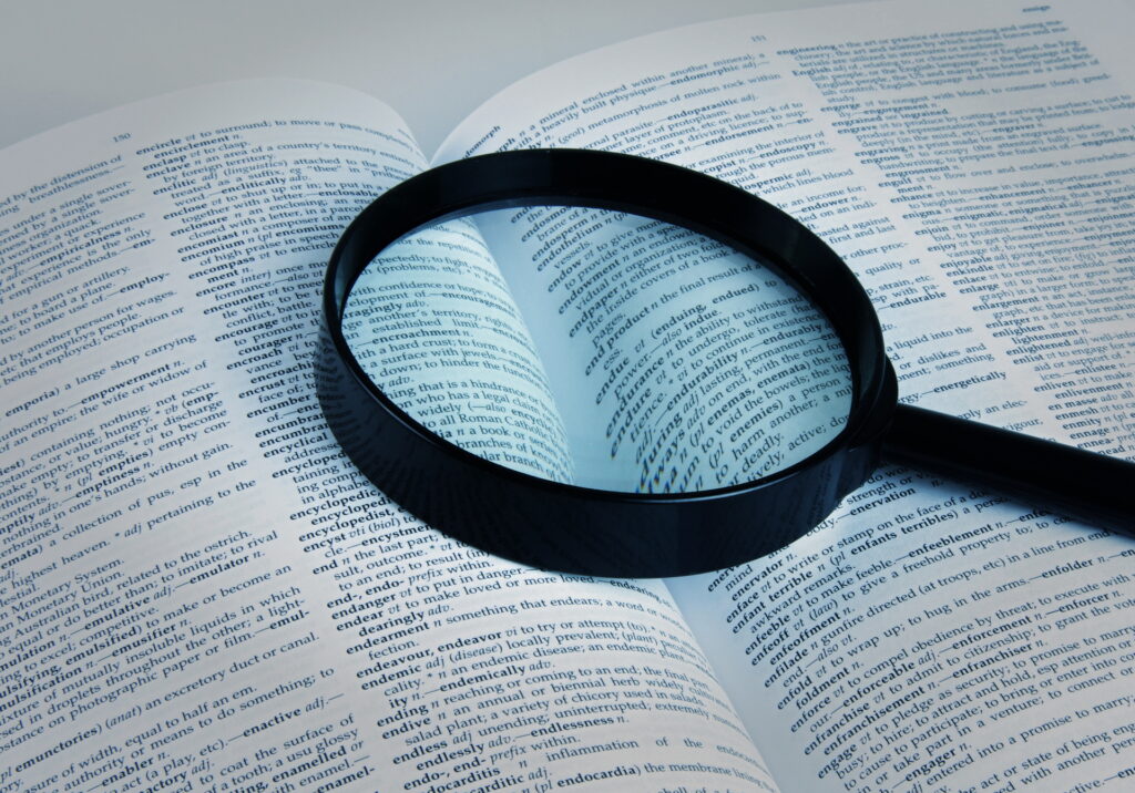 The magnifying glass on the dictionary represents the in-depth research and analysis required to uncover insights in product discovery.