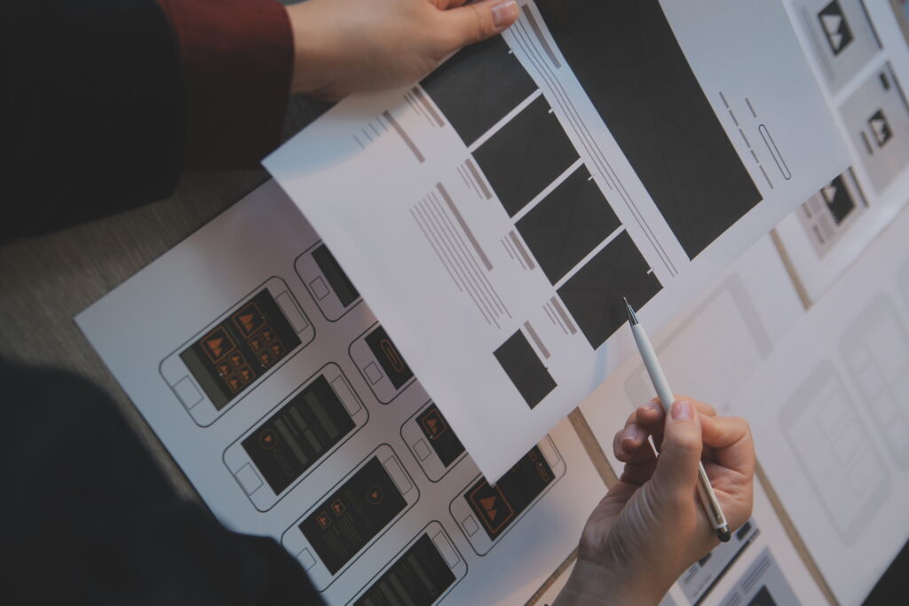 Hands sketching wireframes on paper, representing the planning phase of Digital Experience Design.