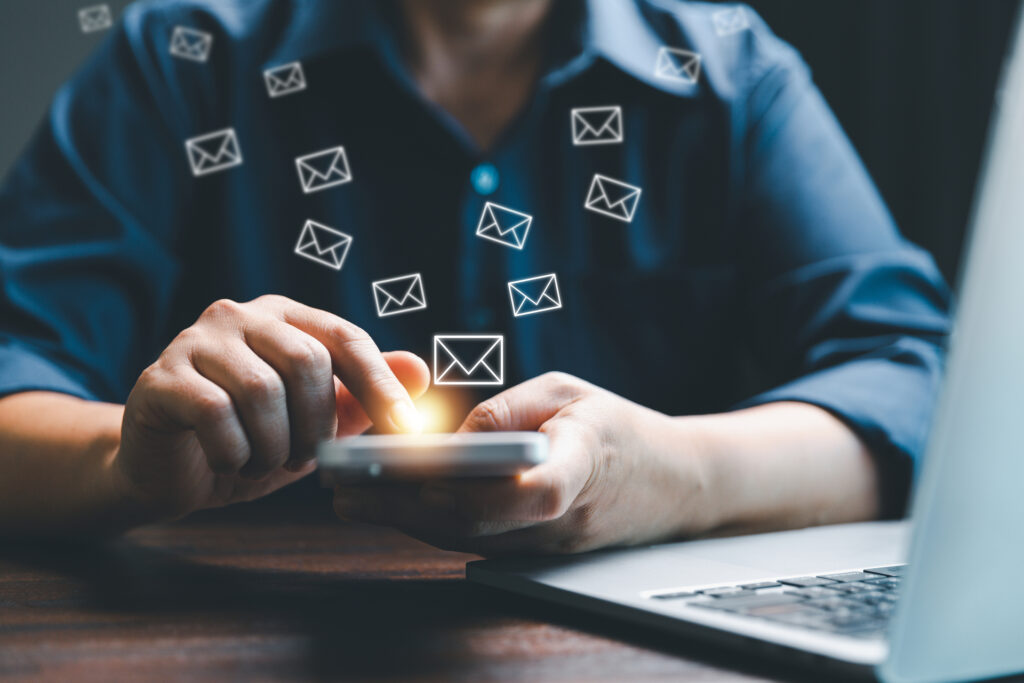 A person interacts with their smartphone, triggering a flurry of email icons that symbolize the dynamic outreach of email marketing campaigns. Perfect for highlighting instant digital communication.