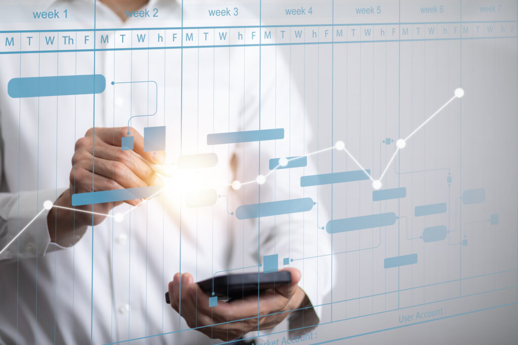 A person in a white shirt is interacting with a digital Gantt chart on a transparent screen, illustrating the planning and scheduling of marketing operations over several weeks.