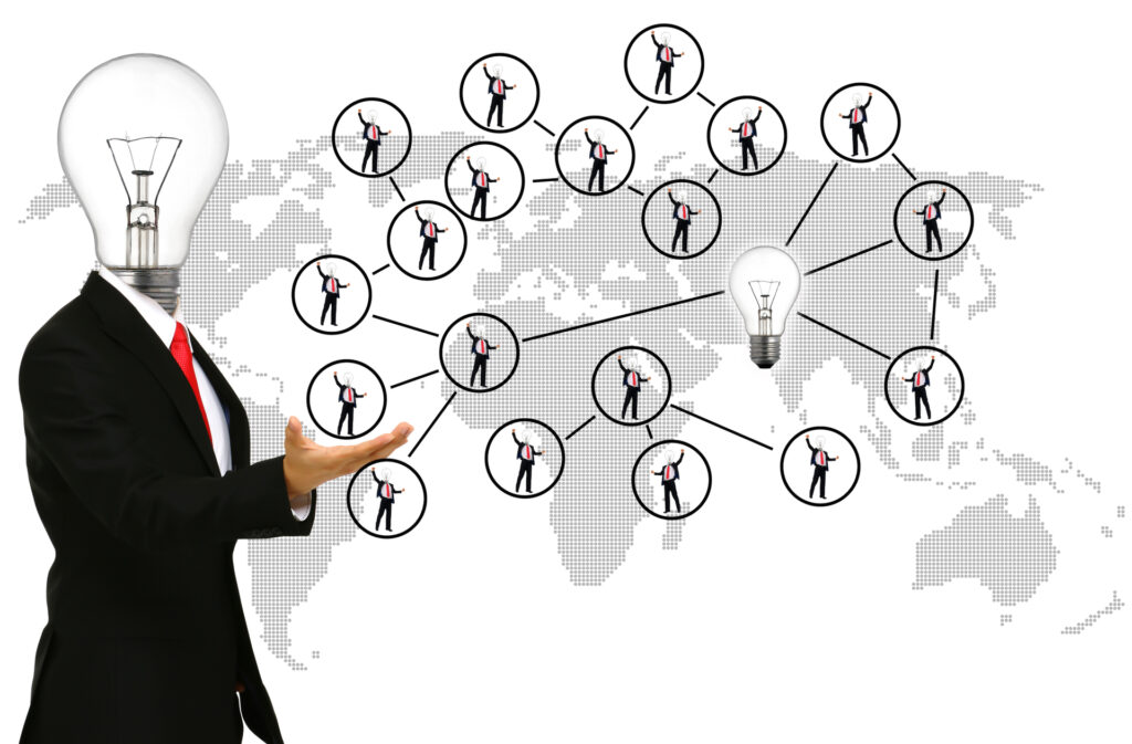 A person with a lightbulb for a head stands in front of a world map connected to smaller lightbulb-headed figures, symbolizing global collaboration in the project discovery phase.