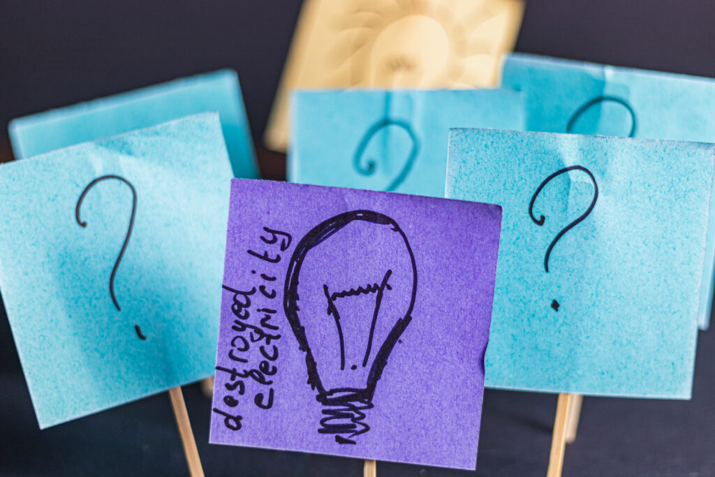 Sticky notes with question marks and a lightbulb sketch represent the brainstorming and ideation phase of product discovery.