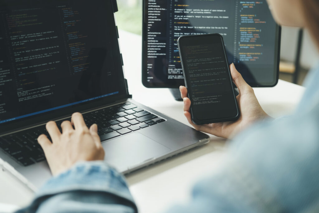 The image showcases a developer working on multiple devices, highlighting the versatility of modern development tools. Low-code platforms further simplify this process by enabling development across different devices and platforms.