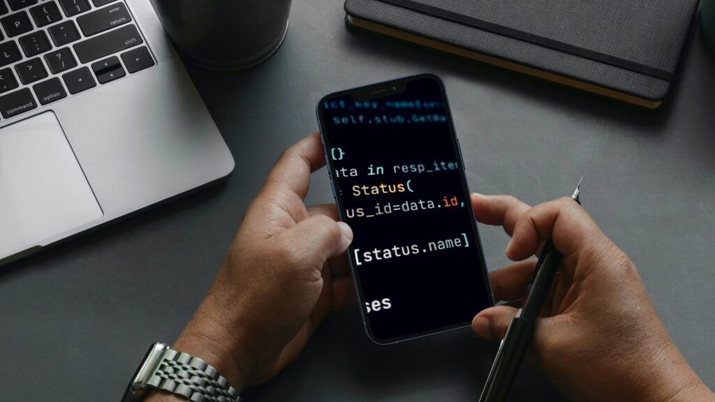 A developer working on a SaaS app, reviewing code on a smartphone, highlighting the portability and accessibility of modern development tools.