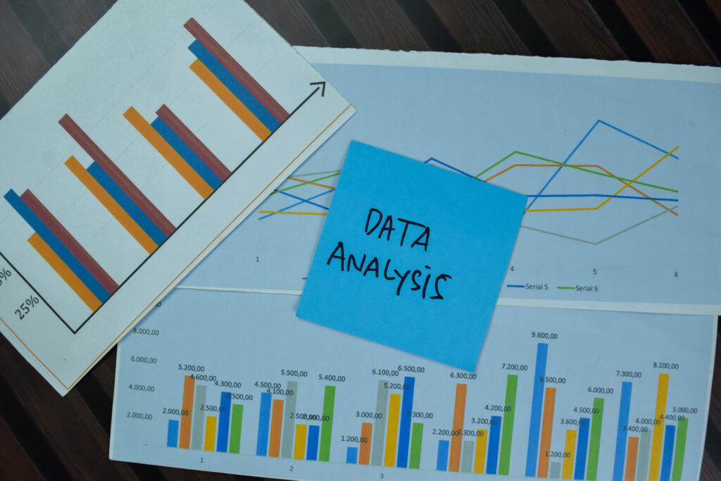 Sticky note with "Data Analysis" text on top of multiple sales graphs and charts.