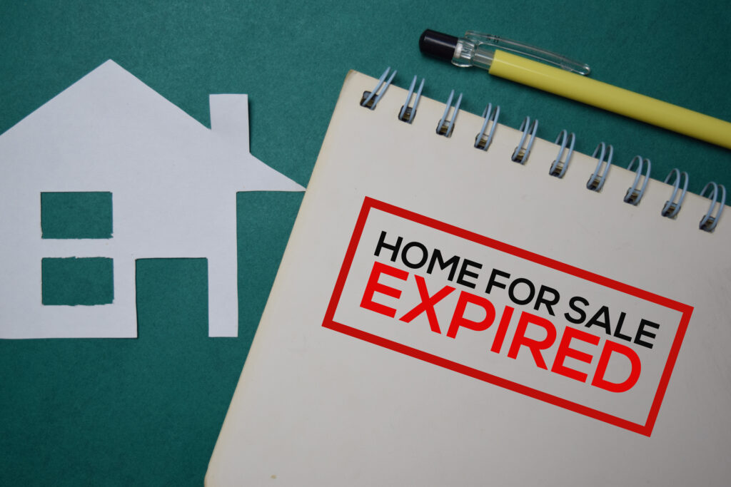 A paper house cutout lies next to a notebook with the words "Home For Sale" stamped in red and the word "EXPIRED" highlighted. This image represents a real estate listing that has expired, meaning the property is no longer available for sale.