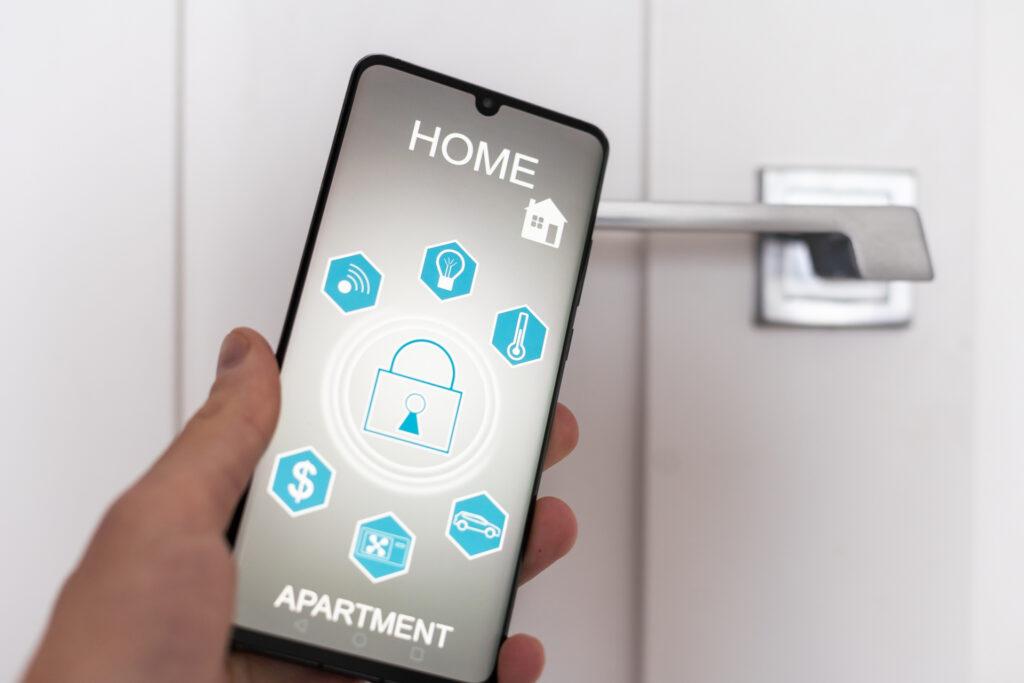 A person uses a smartphone to unlock a door with a smart lock. The phone displays various home automation icons, including security, temperature control, and lighting.