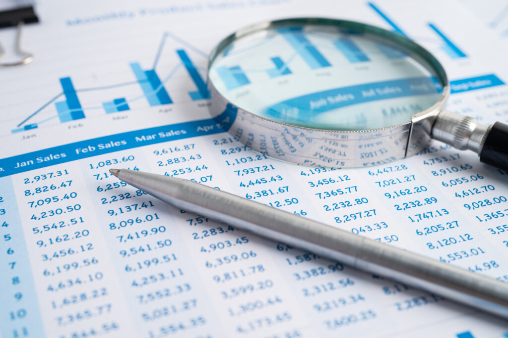 Sales analysis report with magnifying glass and pen highlighting specific data points.