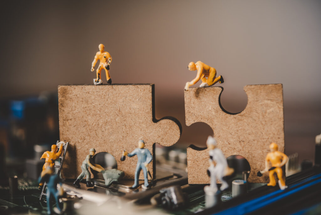 Miniature figures working together to connect two puzzle pieces, representing the collaborative nature of Product Discovery Frameworks.