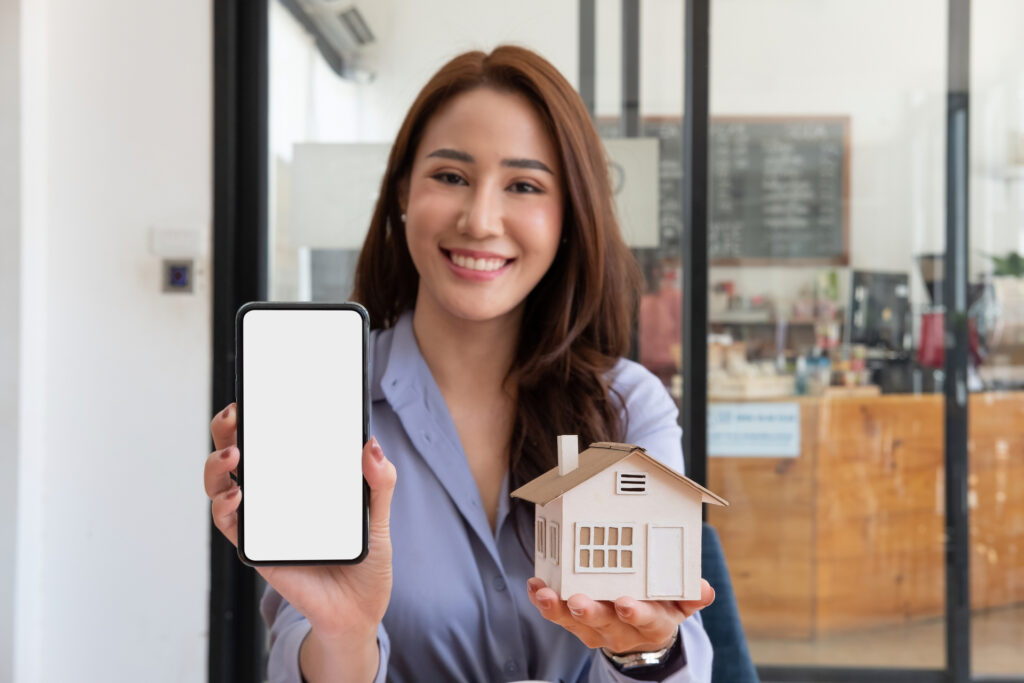 A smiling professional showcases a mobile app and a house model, highlighting innovation in property management solutions