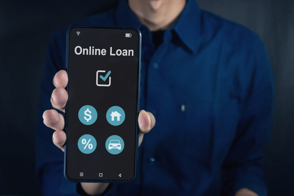 The word "Loan" is shown on a screen, with icons and numbers related to interest rates and loan terms. This image might symbolize the concept of obtaining a loan through an online platform.