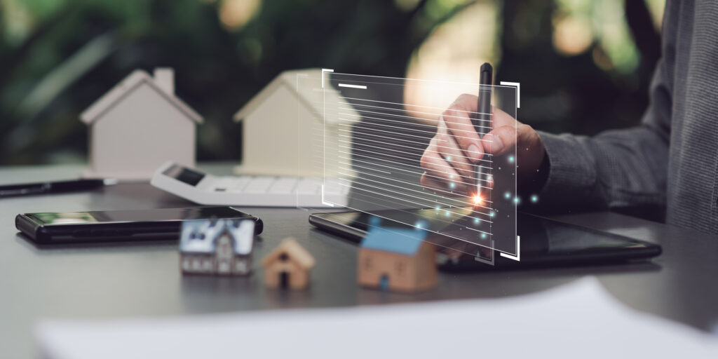 A person using a stylus on a tablet, with a virtual interface and house models, representing the integration of technology in modern real estate practices.