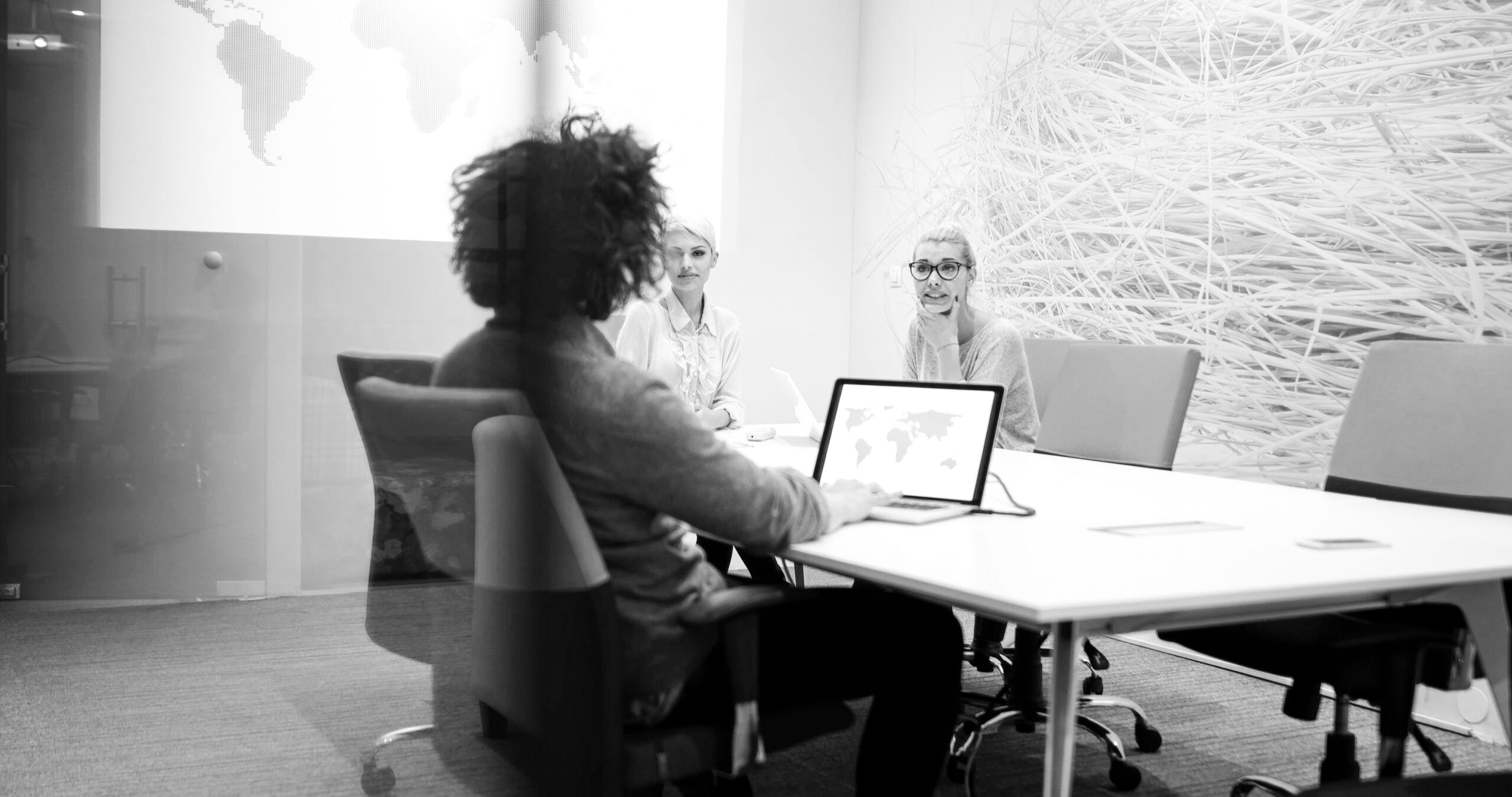 The image you uploaded appears to be a black-and-white photo of a business meeting with three people in a modern conference room