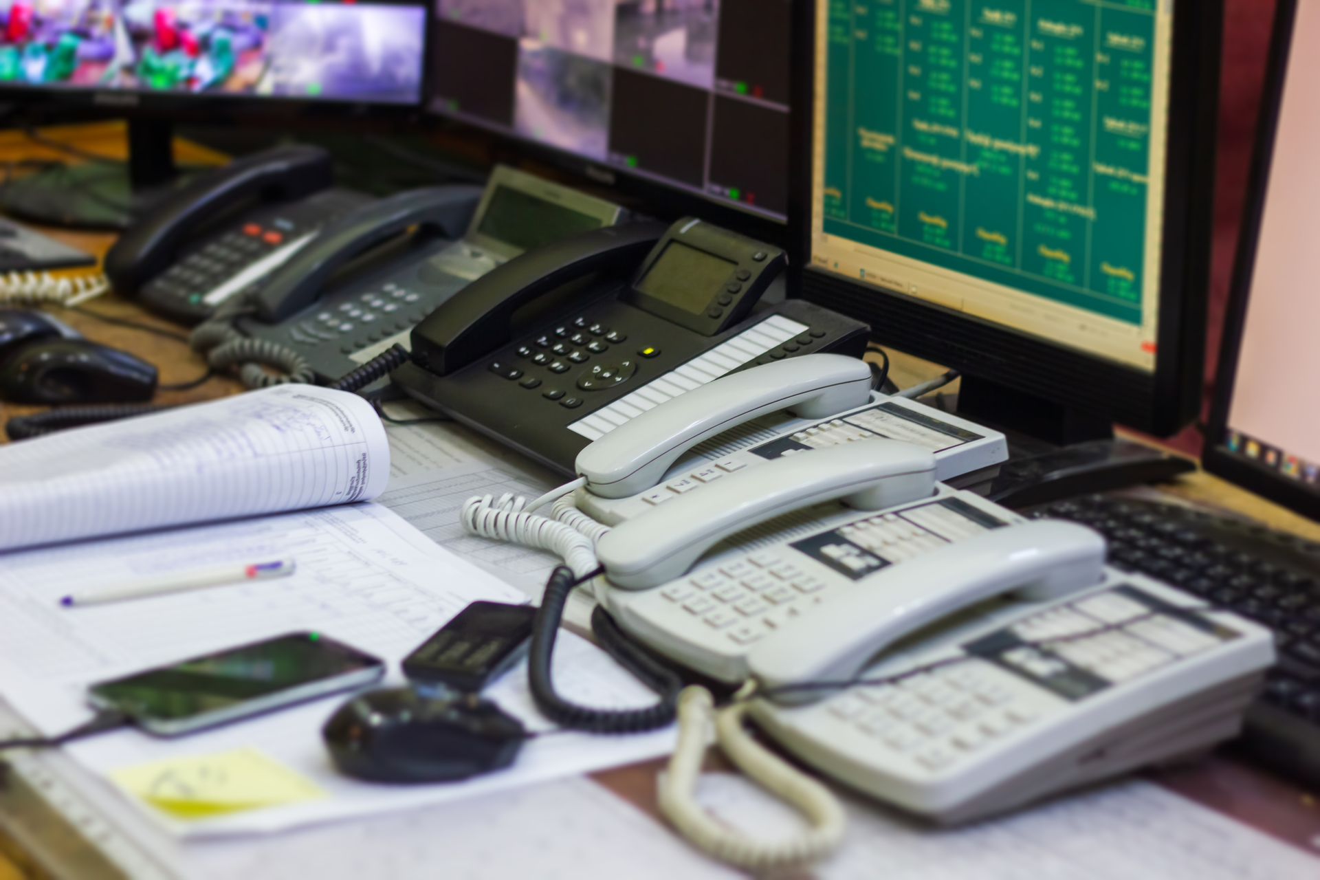 A busy communication center with multiple phones, computers, and monitors.