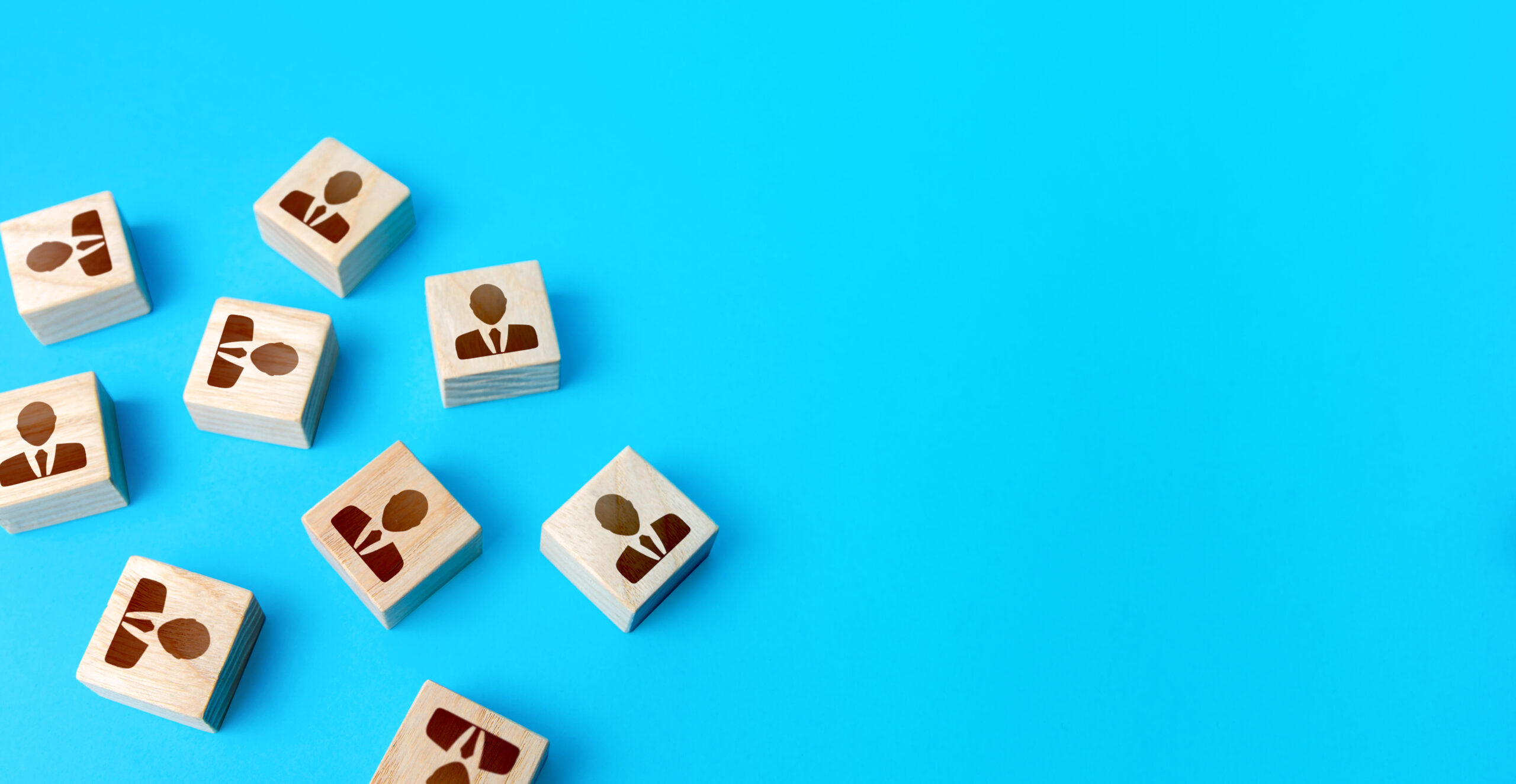 Multiple wooden blocks with people icons scattered across a blue background, symbolizing teamwork and collaboration in customer relationship management