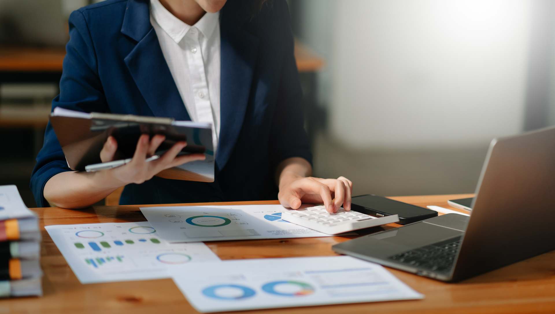 A business professional working at a desk with a calculator, reviewing charts and graphs, highlighting the analytical aspect of sales enablement