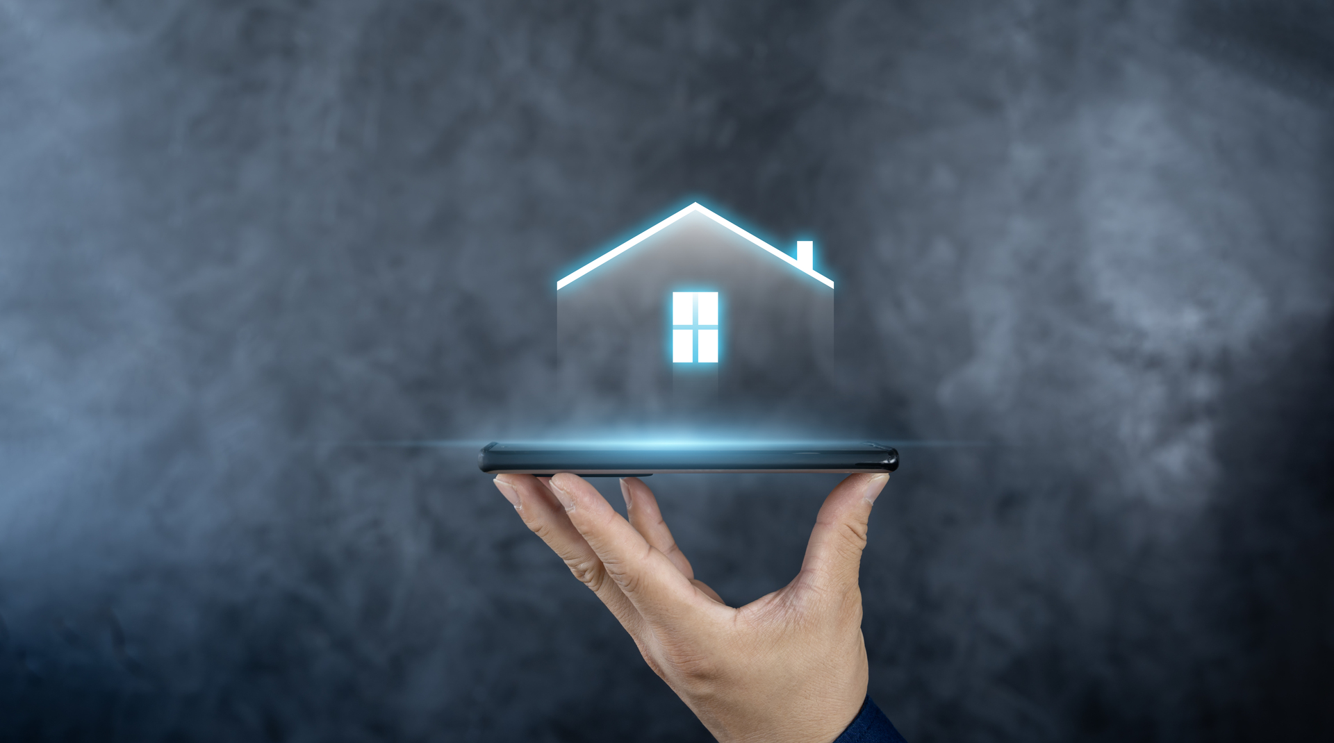 A glowing house icon held in a hand above a smartphone. This symbolizes the potential of automation tools to transform the real estate industry.